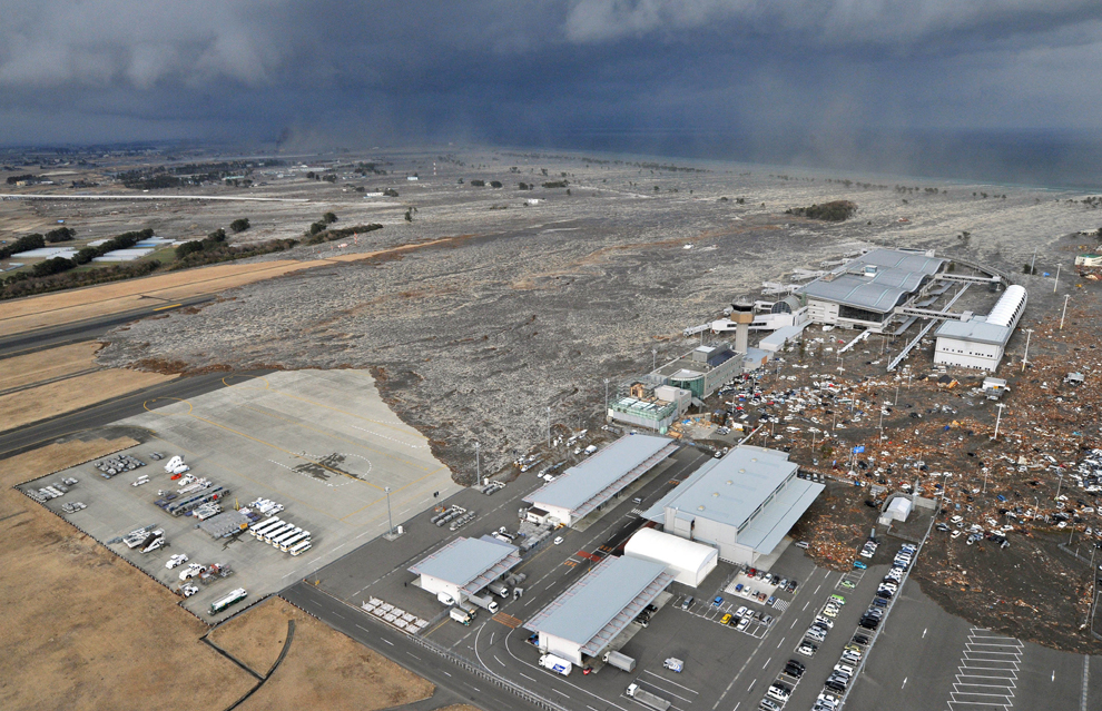 A tsumani triggered by a powerful earthquake makes its way to sweep part of Sendai airport in northern Japan